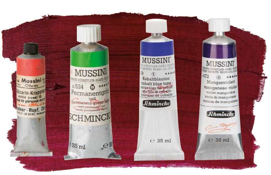 Line of various versions of Schmincke Mussini paint tubes on top of red paint stroke