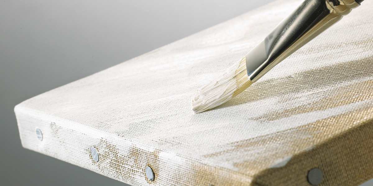 Image of Gesso being applied to canvas with paint brush