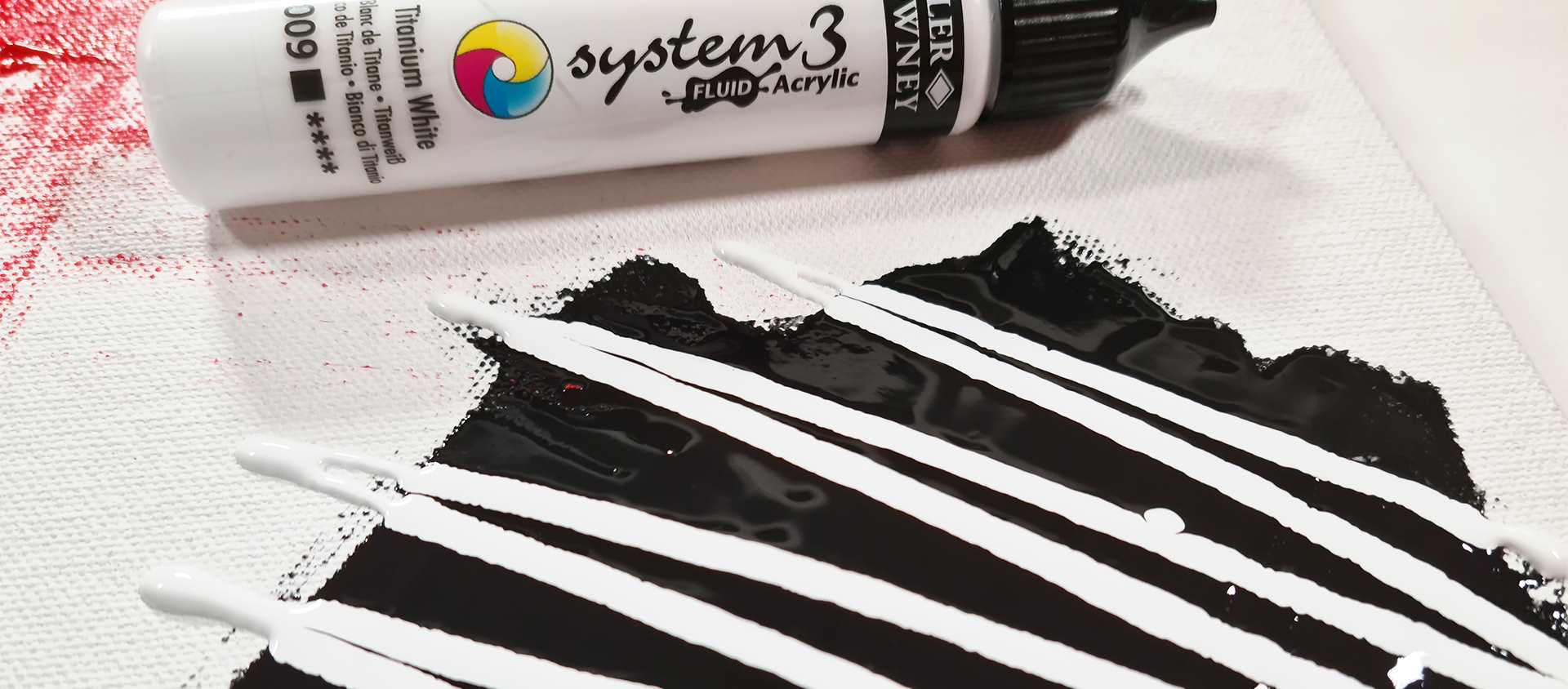 System 3 acrylic fluid tube lying next to black and white fluid acrylic on canvas